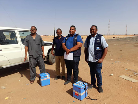 Dr Thabit (extreme right) and Hatim Babiker (second from left) handing over stool samples to the focal points from Egypt, at the Argeen border crossing point. WHO/Sudan 