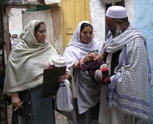 عمال مكافحة شلل الأطفال يعطون نقاط اللقاح لطفل باكستاني