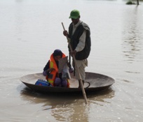 عاملان في التحصين باللقاحات يجدفان في قارب في مياه الفيضانات للوصول إلى الأطفال، منطقة البنجاب، باكستان
