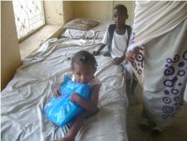 A child sitting on a bed hugging dearly a long-lasting insecticide treated net