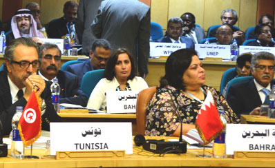 Photo d'une salle de conférences dans laquelle sont assis des hommes et des femmes de tous les pays. Devant eux, une pancarte est posée sur leur bureau, indiquant leur pays ou l'organisation à laquelle ils appartiennent.