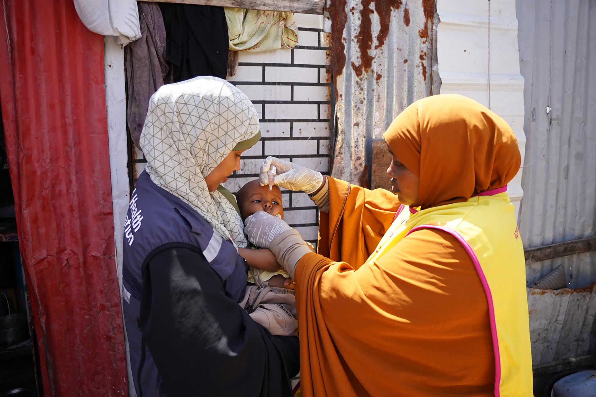 A Somali health worker administers poilo vaccine to a young child during a door-to-door immunization campaign, protecting vulnerable communities from outbreaks.