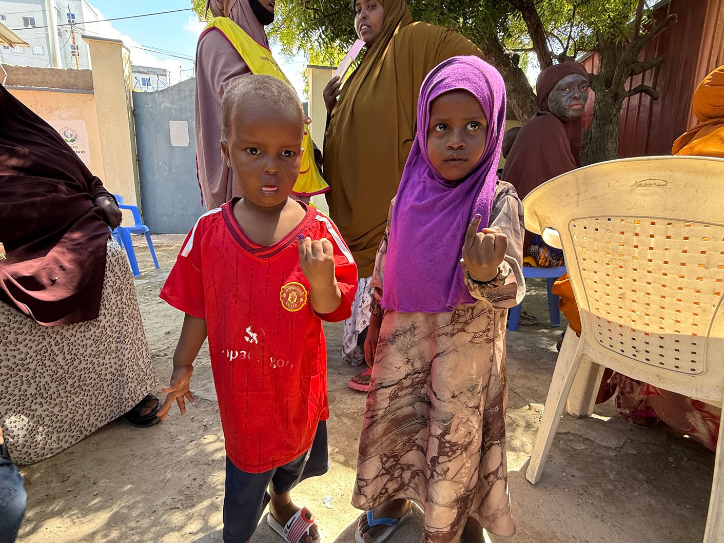 Children proudly show ink-marked fingers after receiving their vaccines.