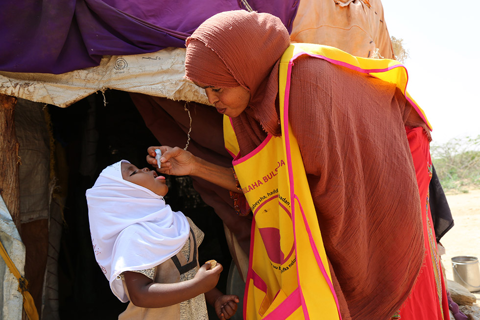 A volunteer vaccinator gives 2 drops of the polio vaccine to a Somali child in August 2019. Despite efforts, many inaccessible areas remain where the programme cannot deliver vaccines. Photo: WHO/Ilyas Ahmed