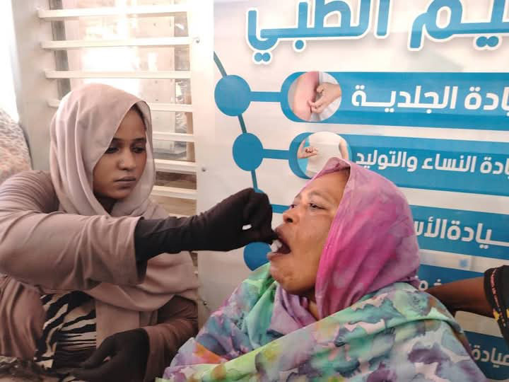A health worker administers an oral cholera vaccine to a woman in Sudan as part of ongoing efforts to curb the spread of the disease and protect high-risk populations.