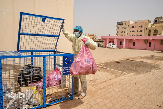 Hussein Sala Habib disposes of medical waste in a container specially set up for this purpose at Omar Ibn Khatab Primary Health Centre in Khartoum.  © WHO/Lindsay Mackenzie