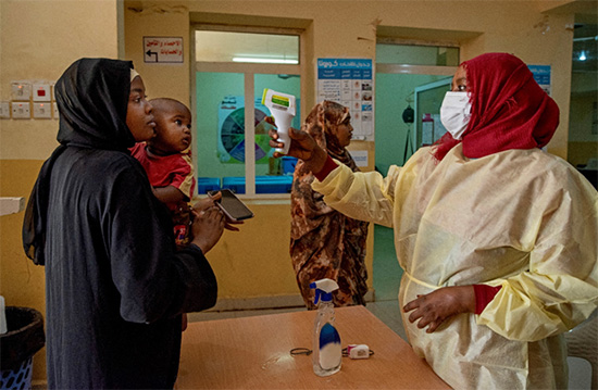 Nurse Nour (right) takes the temperature of incoming patients at a triage point at the entrance to Omar Ibn Khatab Primary Health Centre. She also provides them with hand sanitizer and masks.  © WHO/Lindsay Mackenzie