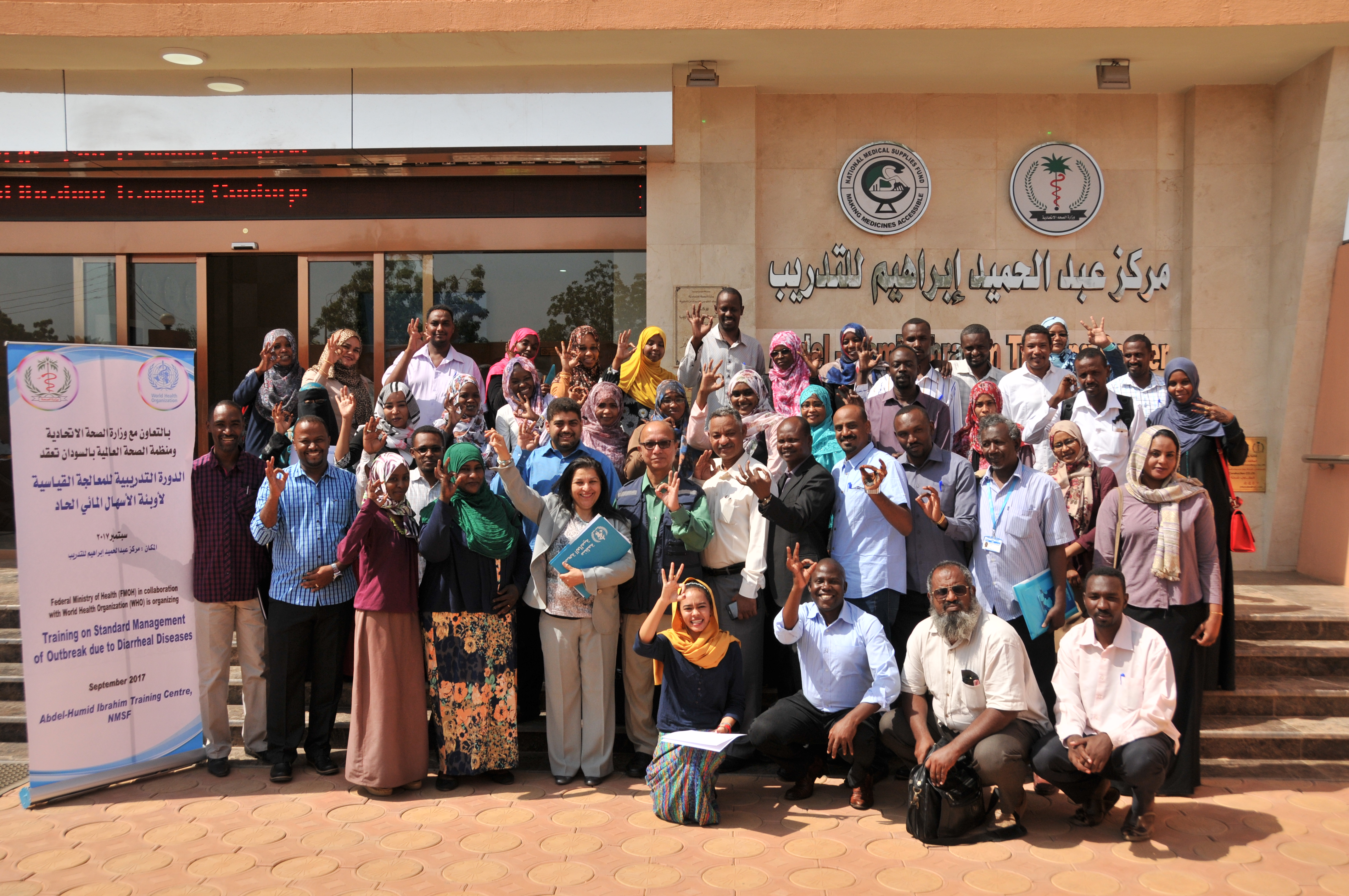 Participants, trainers and WHO Representative for Sudan, Naeema Al Gasseer, hold up the 