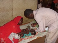 A health care worker from the NGO Mercy Malaysia provides health care services to a baby, watched on by the baby's mother