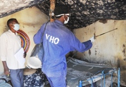 A photo of an environmental health worker spraying a bedroom