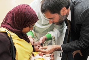 A photo of the WHO Representative in Sudan Dr Anshu Banerjee giving rotavirus vaccine to a child.
