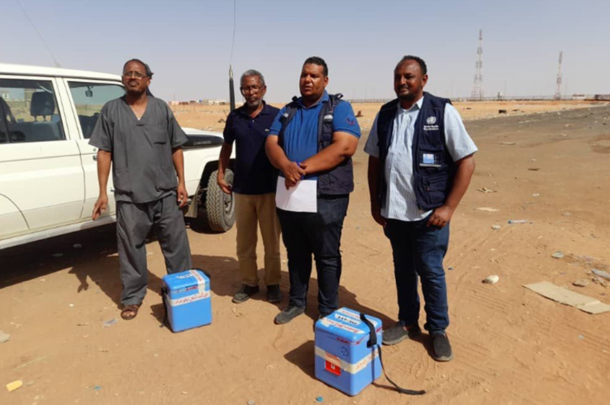 Dr Thabit (extreme right) and Hatim Babiker (second from left) handing over stool samples to the focal points from Egypt, at the Argeen border crossing point. Credit: WHO Sudan