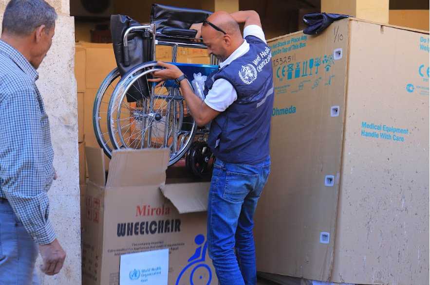 A WHO staff in Egypt handling a wheelchair dispatched by WHO in Egypt as part of medical and surgical supplies to help meet the basic health needs of the tens of thousands fleeing Sudan to Egypt through the Egyptian borders. Credit: WHO