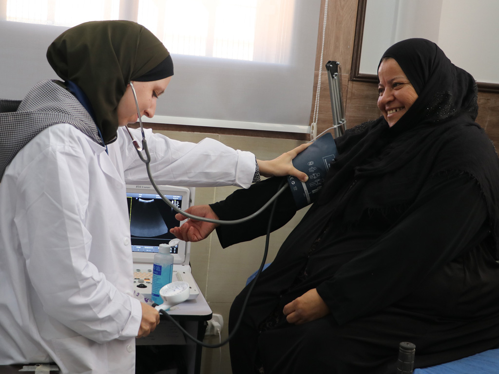 A health worker checks a patient’s blood pressure at Maskaneh Health Centre in rural Aleppo. The facility delivers primary health care services through a WHO-supported implementing partner, ensuring access to essential care for communities in hard-to-reach areas. Photo: WHO