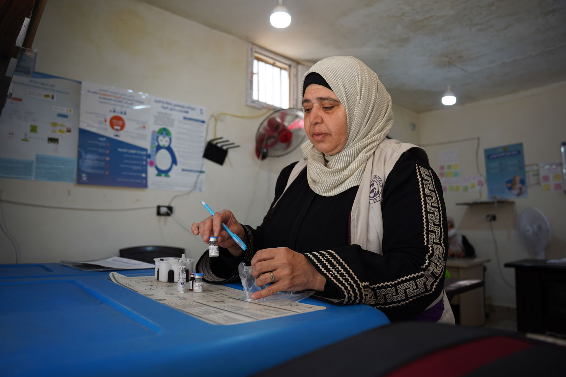 A health worker prepares vaccines before heading out to reach displaced families in Idlib. Photo: WHO
