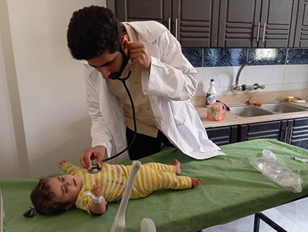 Dr. Hadi Abdul Rahman Al-Sheikh examines 9-month-old Bayan Al-Darfil at Mahkan Public Health Centre in Deir ez-Zor. Photo: WHO