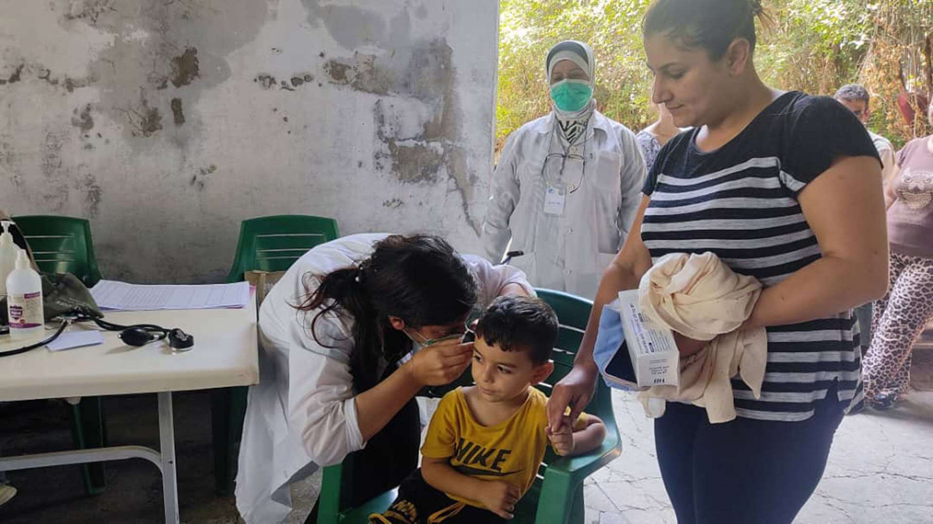 Dr Khairiya Hijazi examines a young boy during a consultation at a mobile health point in Lattakia, where she supports families with pediatric care. Photo: WHO
