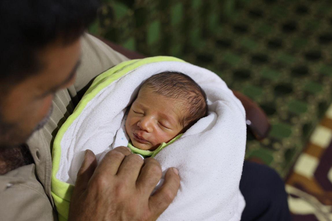 Majed holds his newborn baby after a routine vaccination, committed to protecting his child from preventable diseases from the very first days of life. Photo: WHO