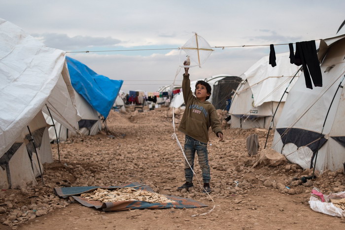 A boy plays with a homemade kite in Ain Issa Camp