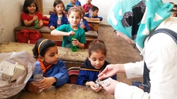 A teacher distributes mebendazole to children as part of the deworming campaign