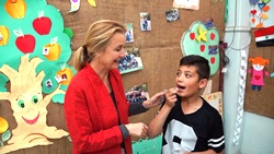 Elizabeth Hoff, WHO Representative in Syria, administers deworming medication to a student