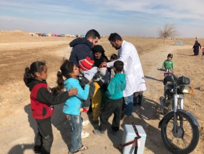 Vaccinators outside an informal tented settlement in Deir Ez-Zor administering polio vaccine to children, as part of the campaign. Photo: WHO 