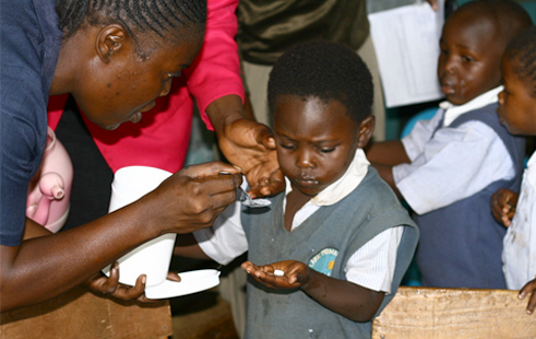 Teacher Administers deworming treatment to a school girl in Kenya