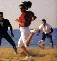 Un groupe de jeunes, garçons et filles, jouent au ballon sur la plage.