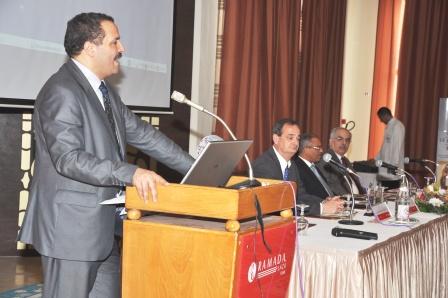 Le Dr Abdellatif Mekki, Ministre de la Santé publique de Tunisie, se tient à la tribune au premier plan, où il prononce un discours. Des invités sont assis à une table en arrière-plan.