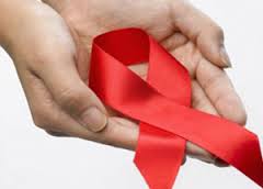 L'image nous montre des mains tendues apportant le ruban rouge, signe de la lutte contre le sida