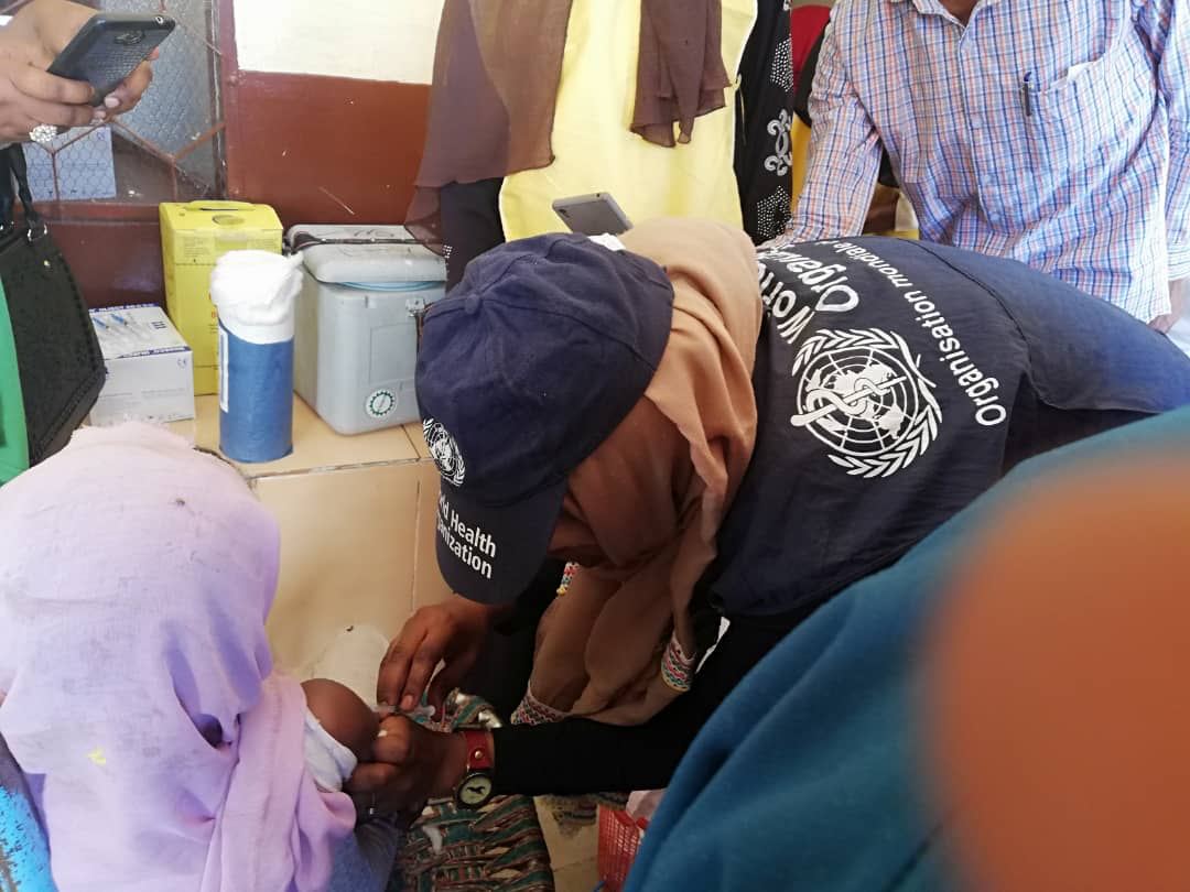 WHO_technical_Officer_administers_the_measles_vaccine_to_a_child_in_South_Darfur_State_Suda_on_8_April_2019 WHO_technical_Officer_administers_the_measles_vaccine_to_a_child_in_South_Darfur_State_Suda_on_8_April_2019