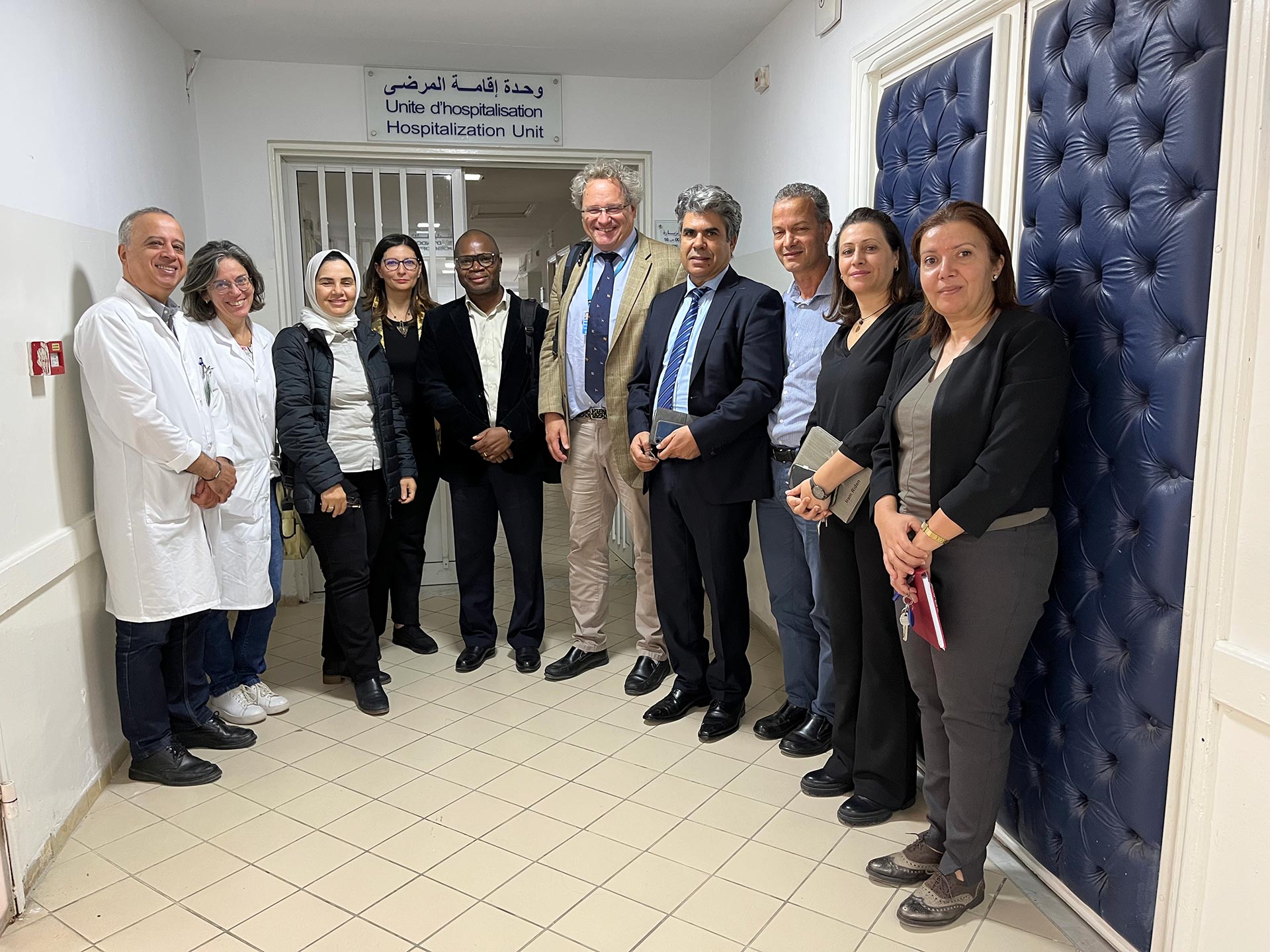A group of healthcare staff and visitors standing together in a hospital corridor near the entrance to the hospitalization unit