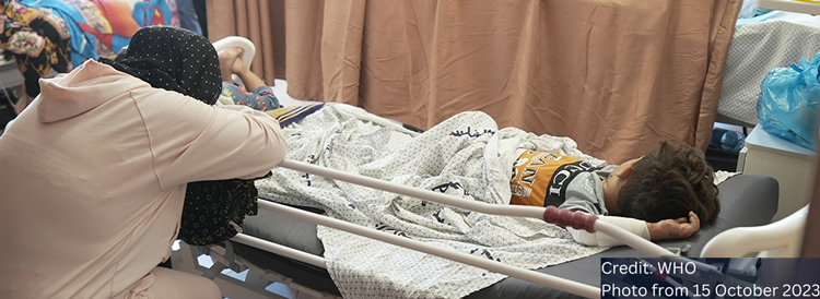امرأة تضع رأسها بين يديها وتتكئ على سرير المستشفى الذي يرقد عليه طفل.