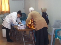Umm Luai'a, a Ministry of Health nurse, registering young children in Al Zaatari