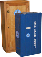 Picture of a blue trunk library in front of a mini library contained in a wooden chest