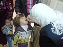 A child is administered oral polio vaccine in Homs