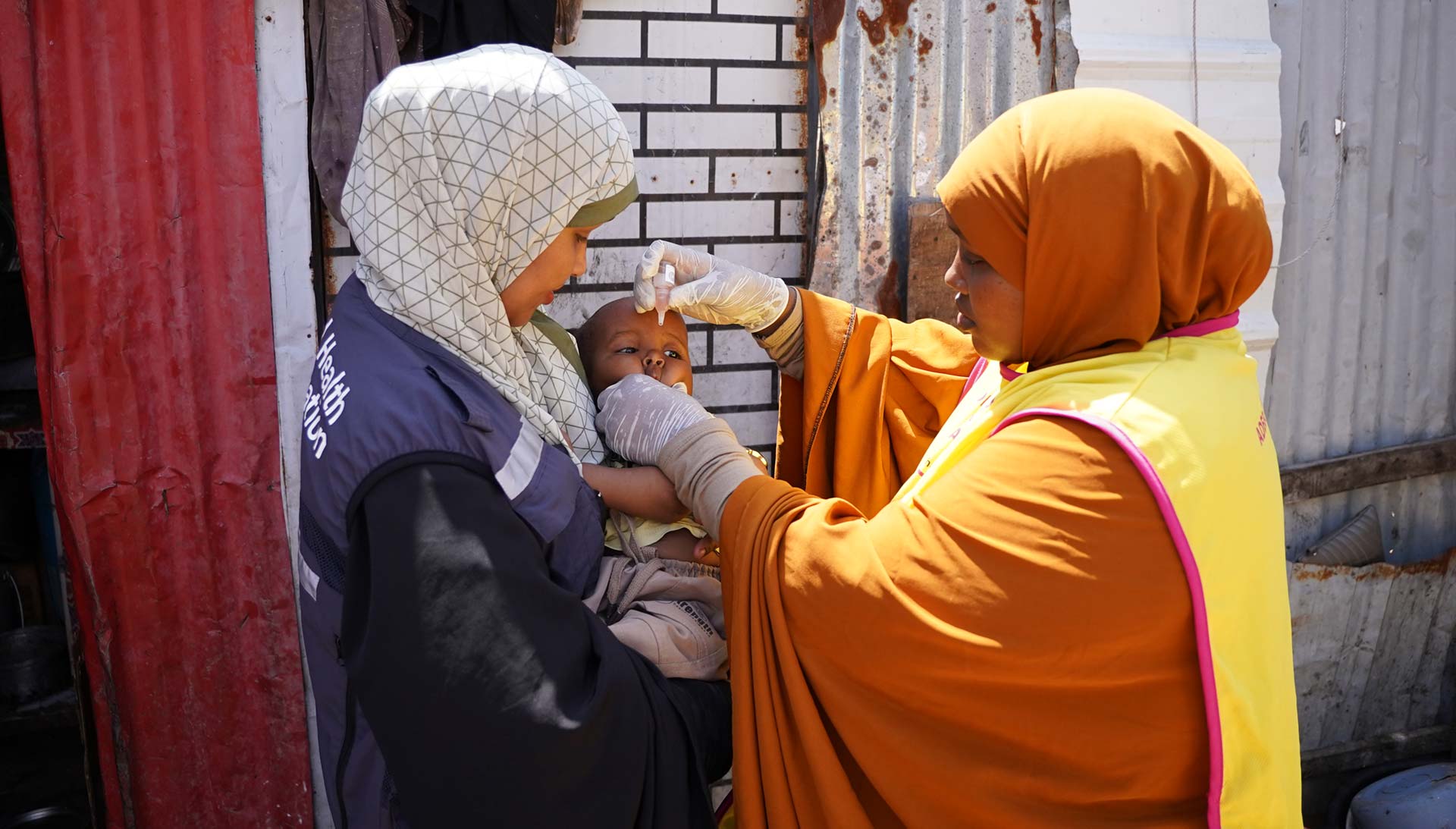 Somali Health worker administers polio vaccine to a young child during a door-to-door immunization campaign