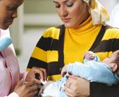 A health care worker vaccinates a baby held by its mother
