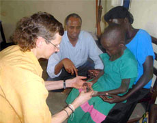 Health workers in Uganda examine a young girl showing symptoms of nodding syndrome