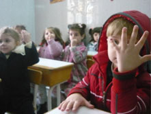 Children in a Homs kindergarten hold up their hands to show they have been vaccinated