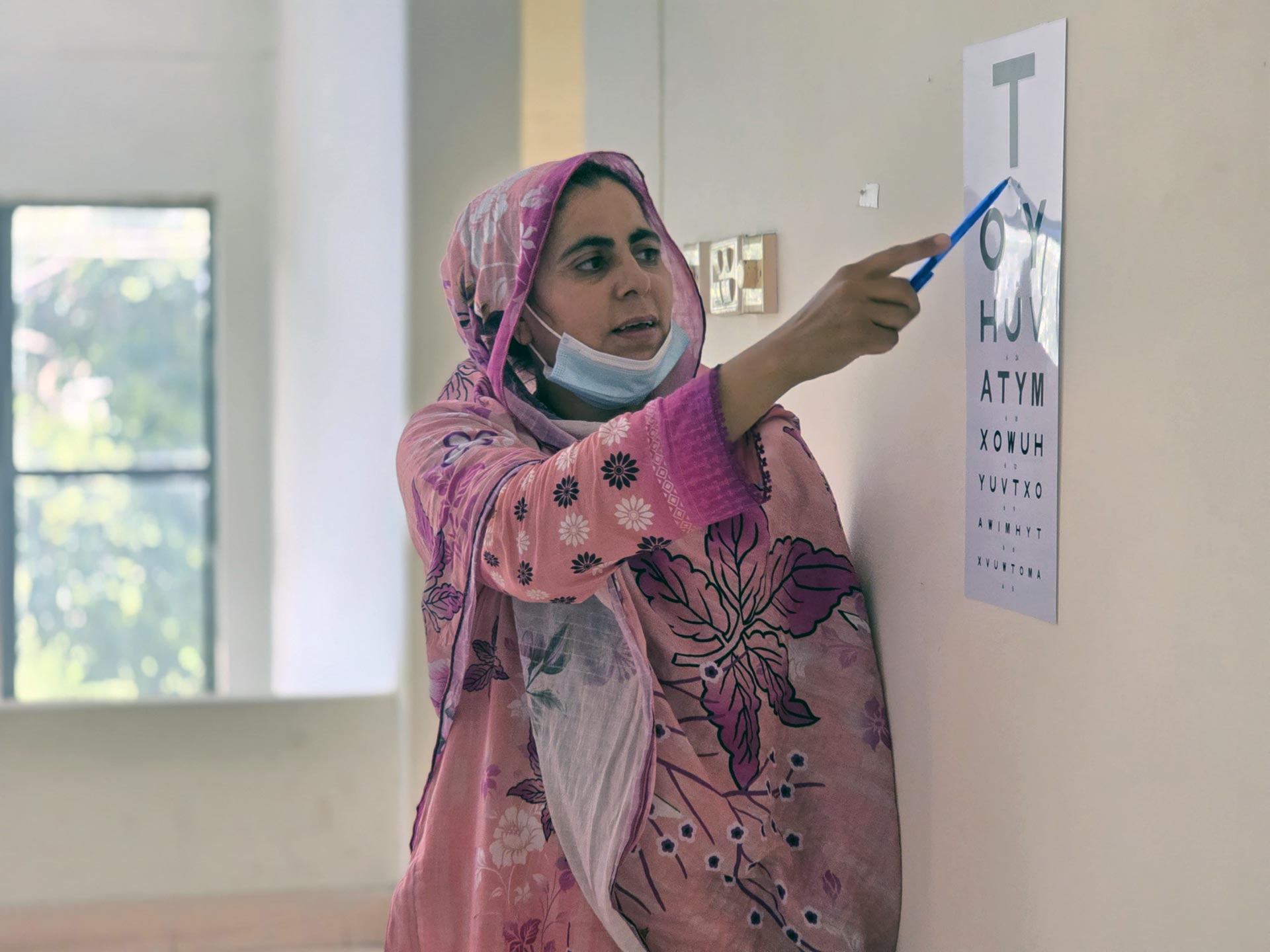 A health worker conducts a vision screening using an eye chart at a community clinic.