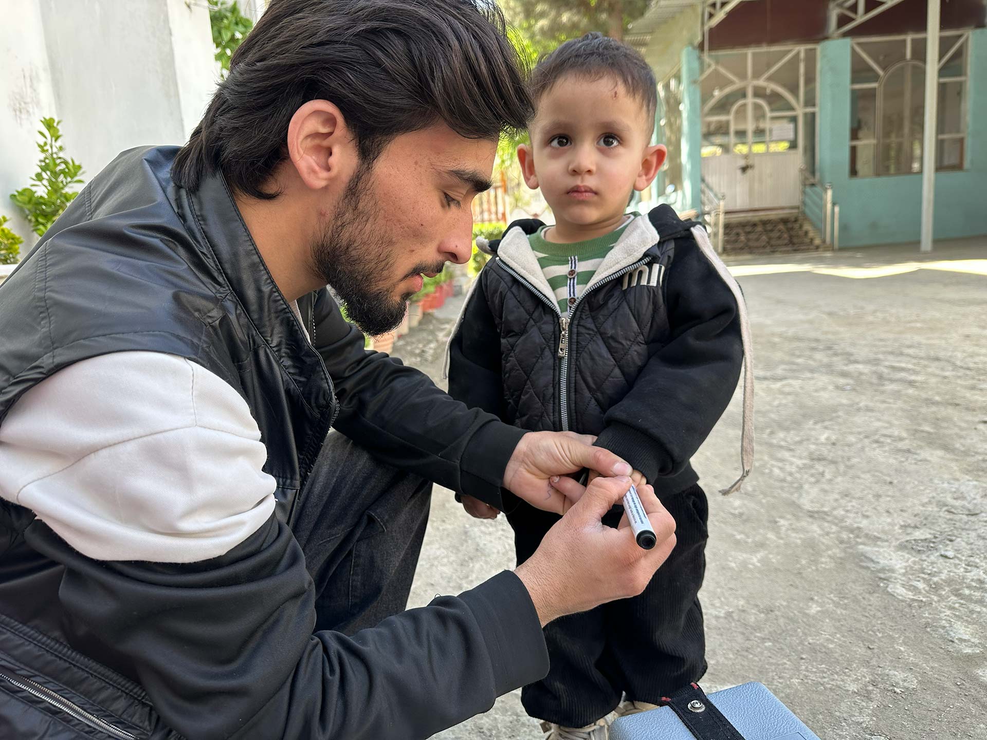 Rostam Mohebi, a polio vaccinator, marks a child’s finger after polio vaccination during the April 2026 National Immunization Days (NID) in Kabul, Afghanistan. Photo credit: Khesraw Omid Farooq / WHO Afghanistan