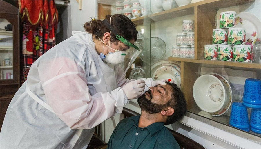 Dr. Samreen Khalil, WHO Polio Eradication Officer, collects a sample from Muhammad Shabir at his residence in Peshawar, Pakistan, to test for COVID-19.