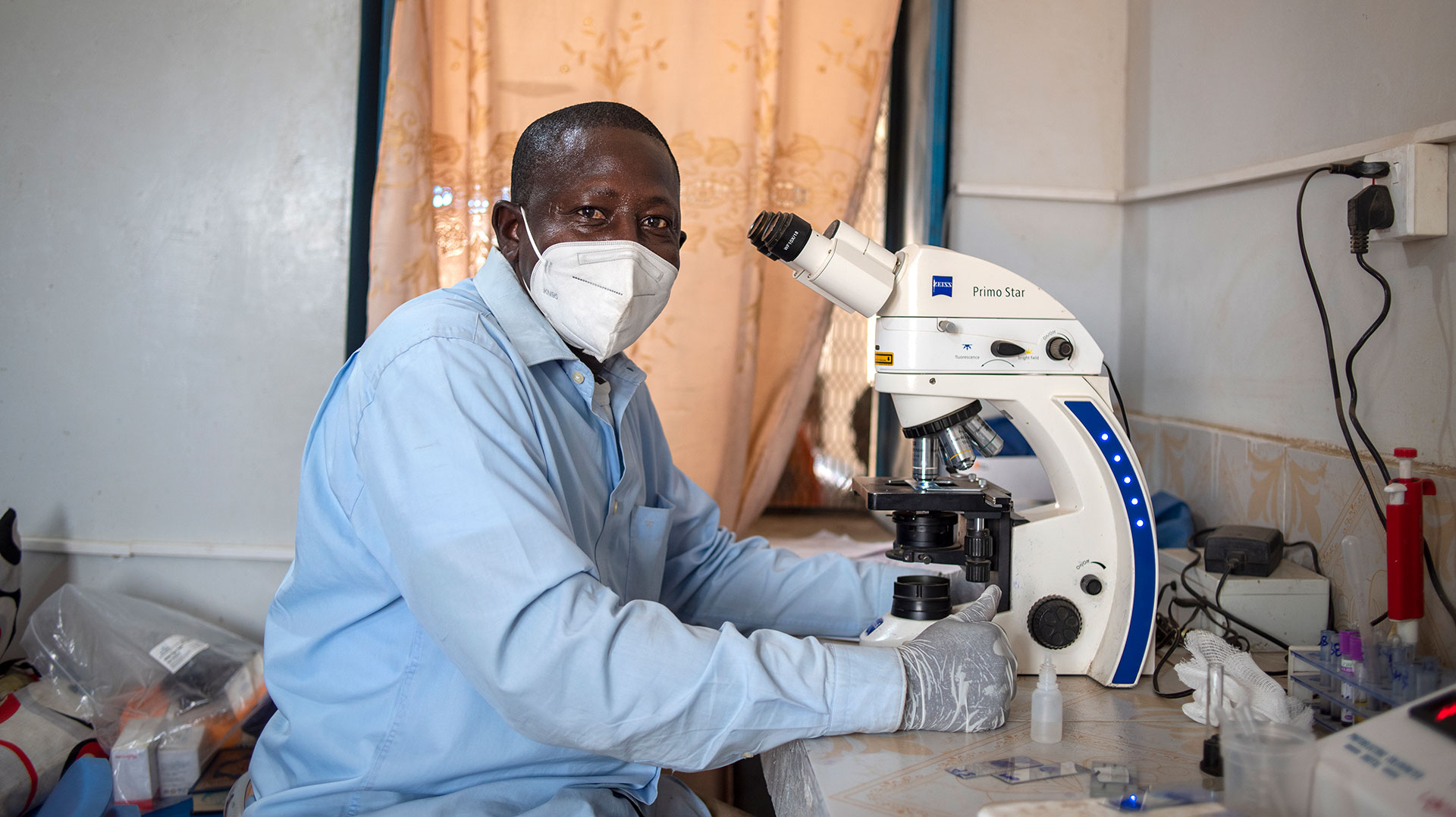 On 26 April 2022, a laboratory technician looks at blood slides for malaria in a laboratory in a health facility for women and children in Abu Shouk IDP camp in North Darfur