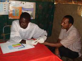Community health volunteer in Sudan conducting a rapid diagnostic test (RDT) in a rural health post
