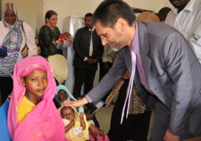 WHO Representative in Sudan Dr Anshu Banerjee touches the first infant to receive PCV13 vaccine