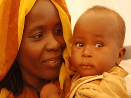 A Sudanese mother smiling as she holds her healthy baby
