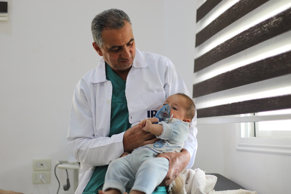 A paediatrician at the centre provides urgent care to an infant with respiratory distress. Photo credit: WHO