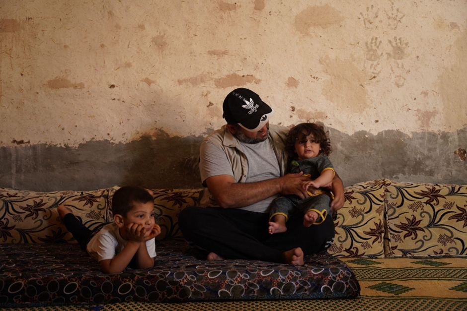 Abu Tarek sits with his youngest son while one of his older children rests nearby. Photo credit: WHO