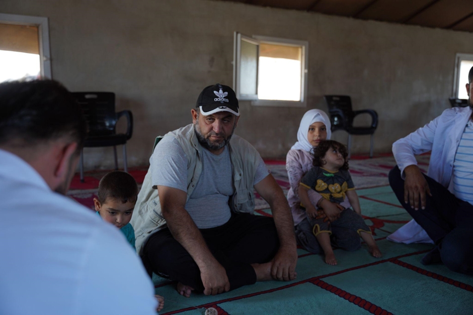 Abu Tarek speaks with a health worker during a vaccination session at the camp. Photo credit: WHO 